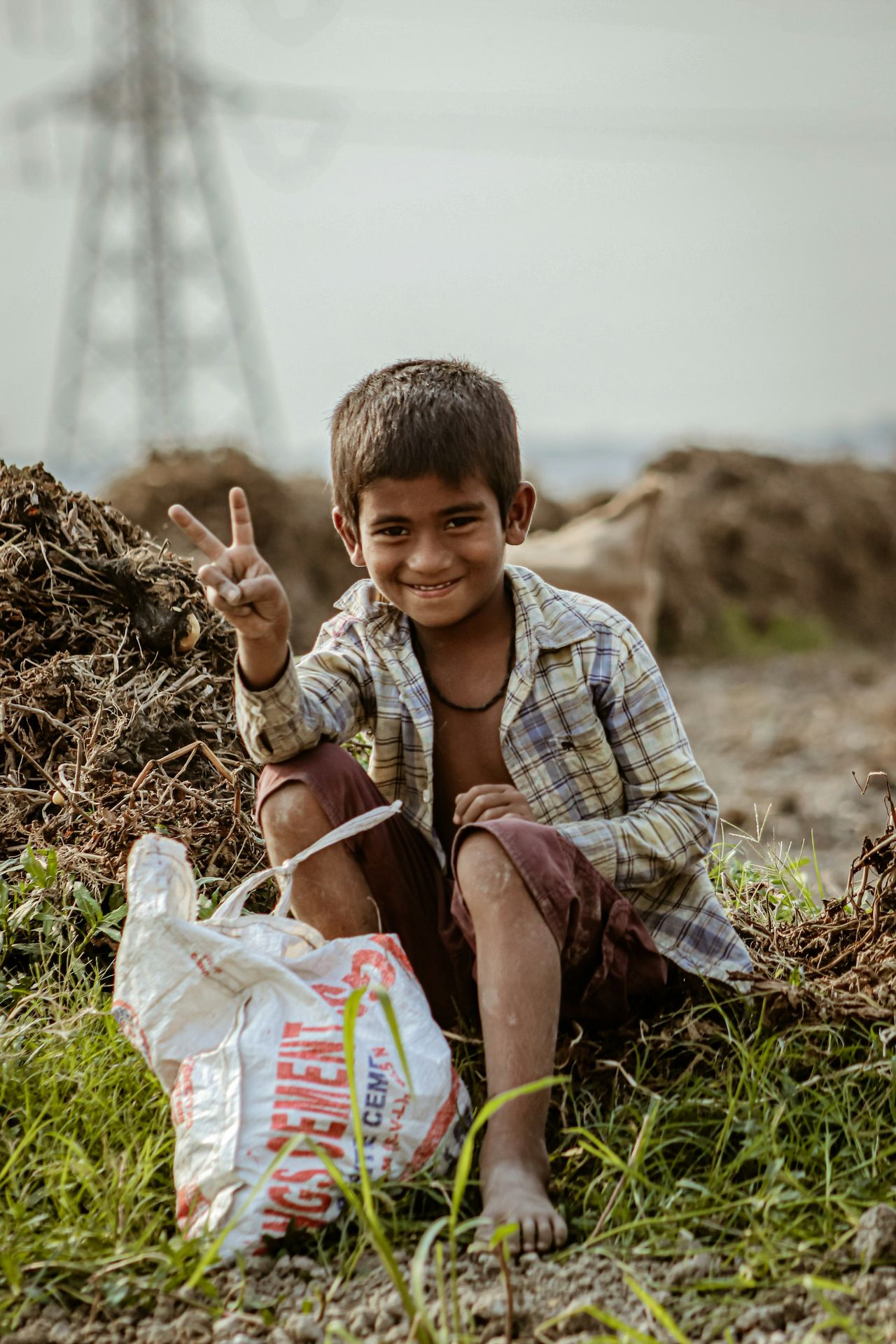 a young boy sitting on the ground with a bag of food